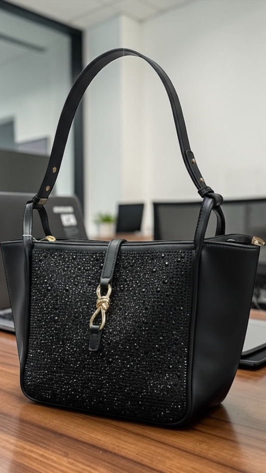 Black handbag on a desk with a blurred office background